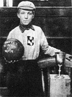 B/W Photograph of Len Grant in cap and shirt holding ball next to trophy