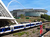 Photograph of a Chiltern Railways' service calling at Wembley Stadium Station under White Horse Bridge with Wembley Stadium in the background.