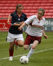 Two girls playing football, one is trying to tackle the other for the ball